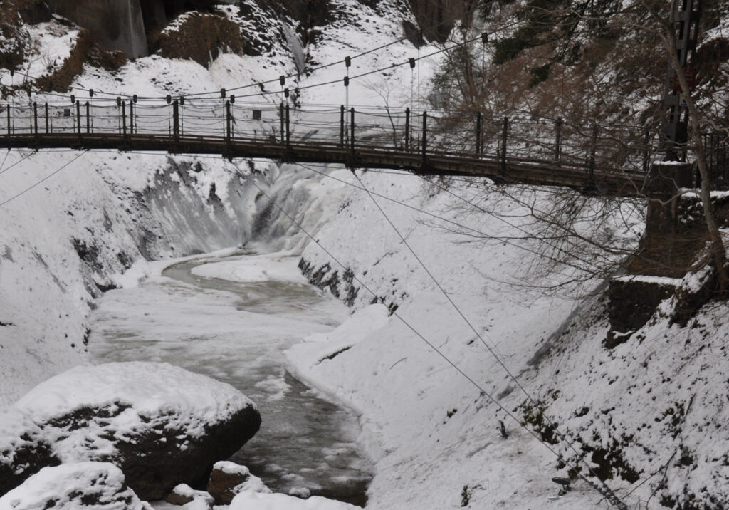 吊り橋を上に眺める光景は、まるですべての雑音を雪が吸い込んでしまったかのような、深い静寂に満ちている。
